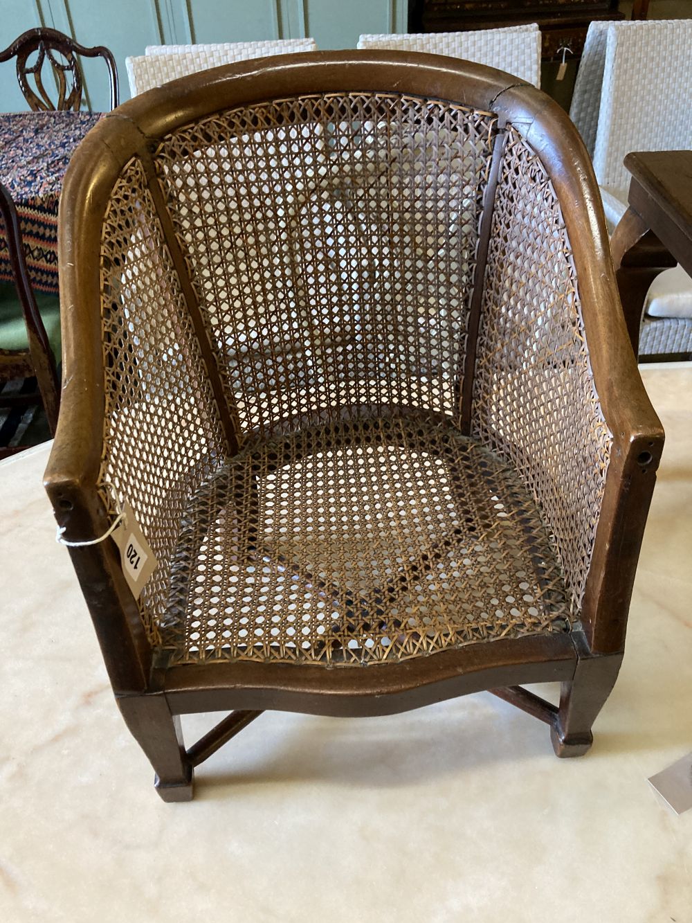 A childs caned mahogany bergere on table stand